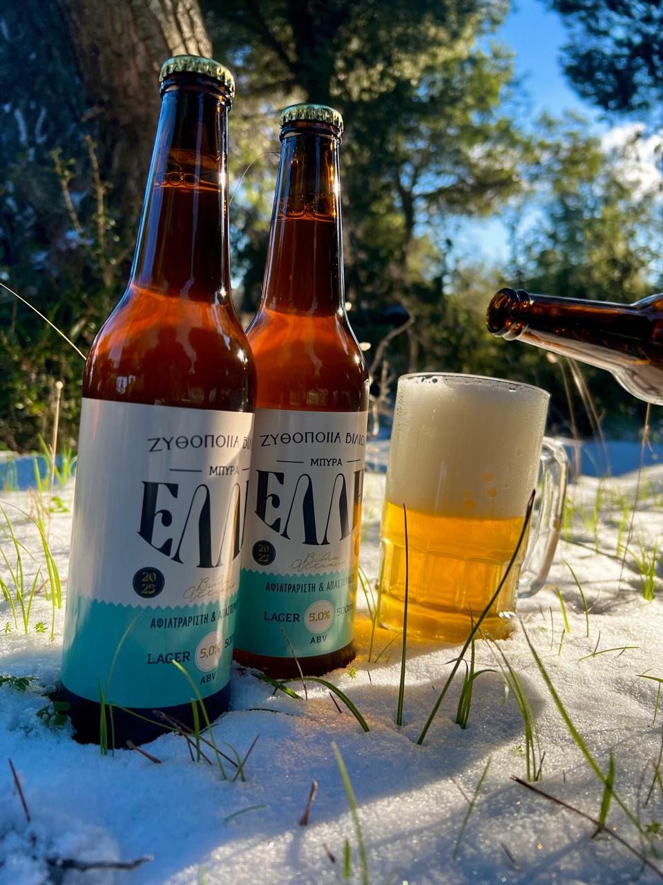 Μπύρες ΕΛΛΗ Lager και ποτήρι μπύρας στο χιόνι, μέσα στο δάσος
